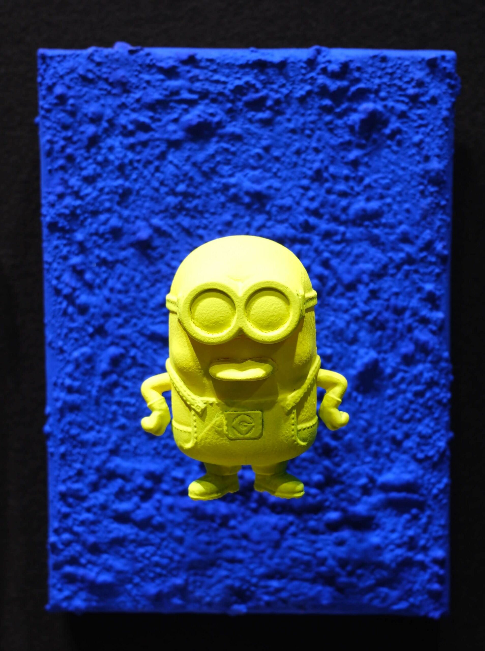 Seb Machten contemporary pop art sculpture with fluorescent orange minion-inspired figure on ultramarine textured surface