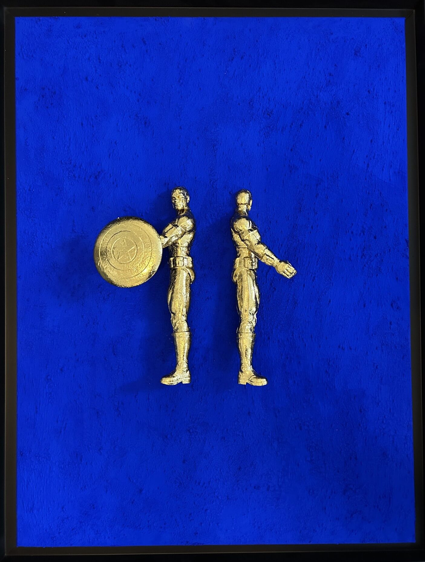 Seb Machten contemporary artwork with two gold superhero figures back to back on deep ultramarine surface