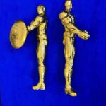 Seb Machten contemporary artwork with two gold superhero figures back to back on deep ultramarine surface
