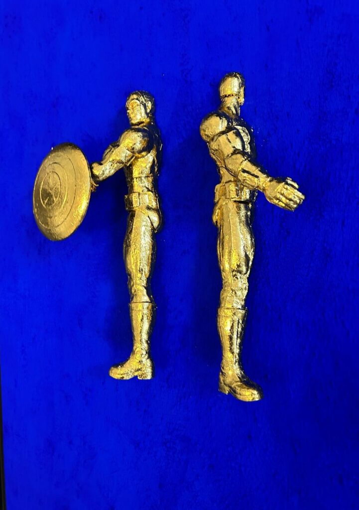 Seb Machten contemporary artwork with two gold superhero figures back to back on deep ultramarine surface