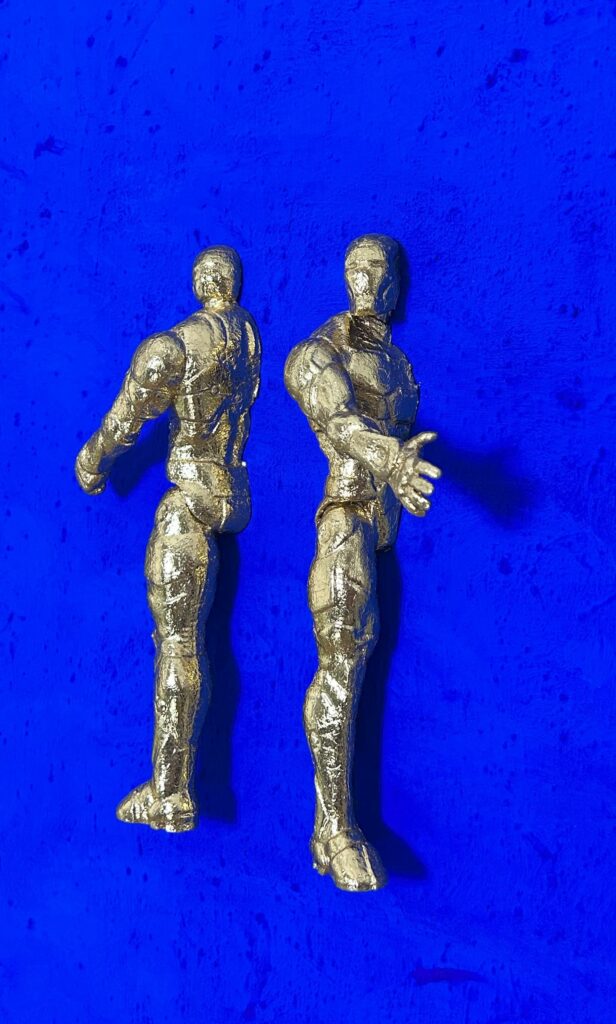 Seb Machten contemporary artwork with two gold superhero figures back to back on deep ultramarine surface