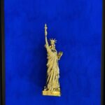 Seb Machten contemporary artwork with gold Statue of Liberty sculpture on ultramarine blue surface