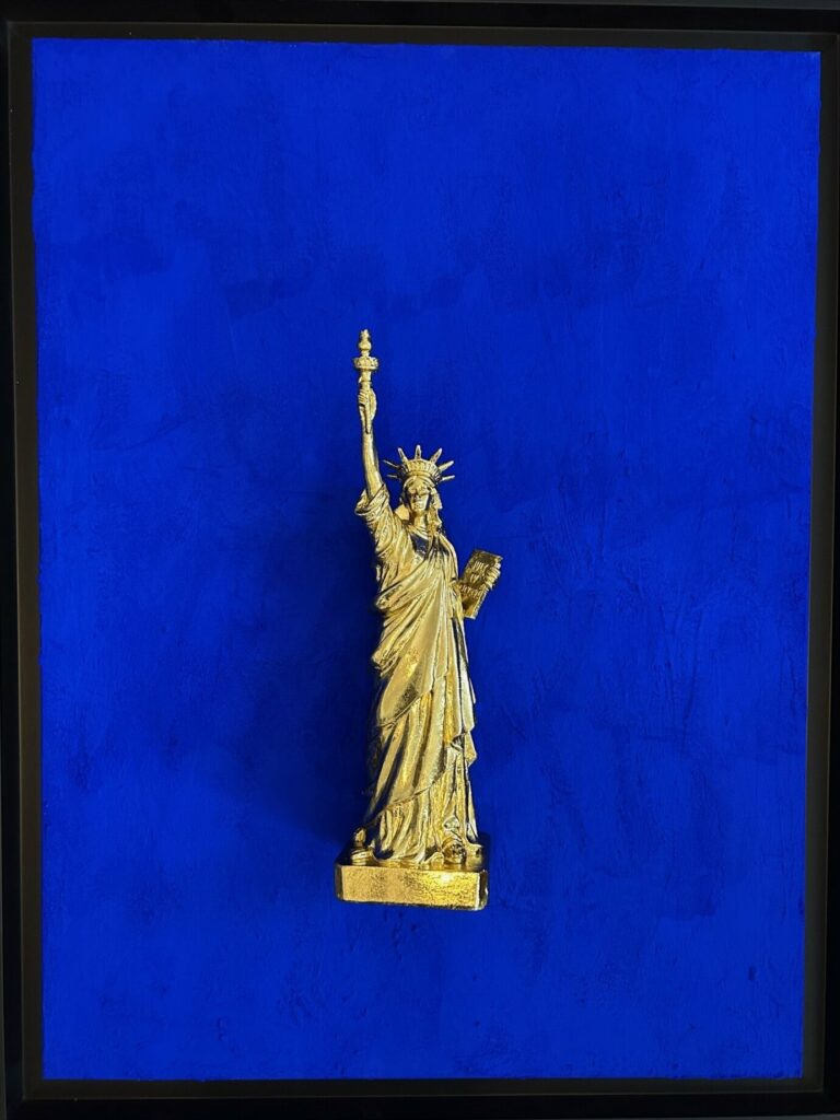 Seb Machten contemporary artwork with gold Statue of Liberty sculpture on ultramarine blue surface