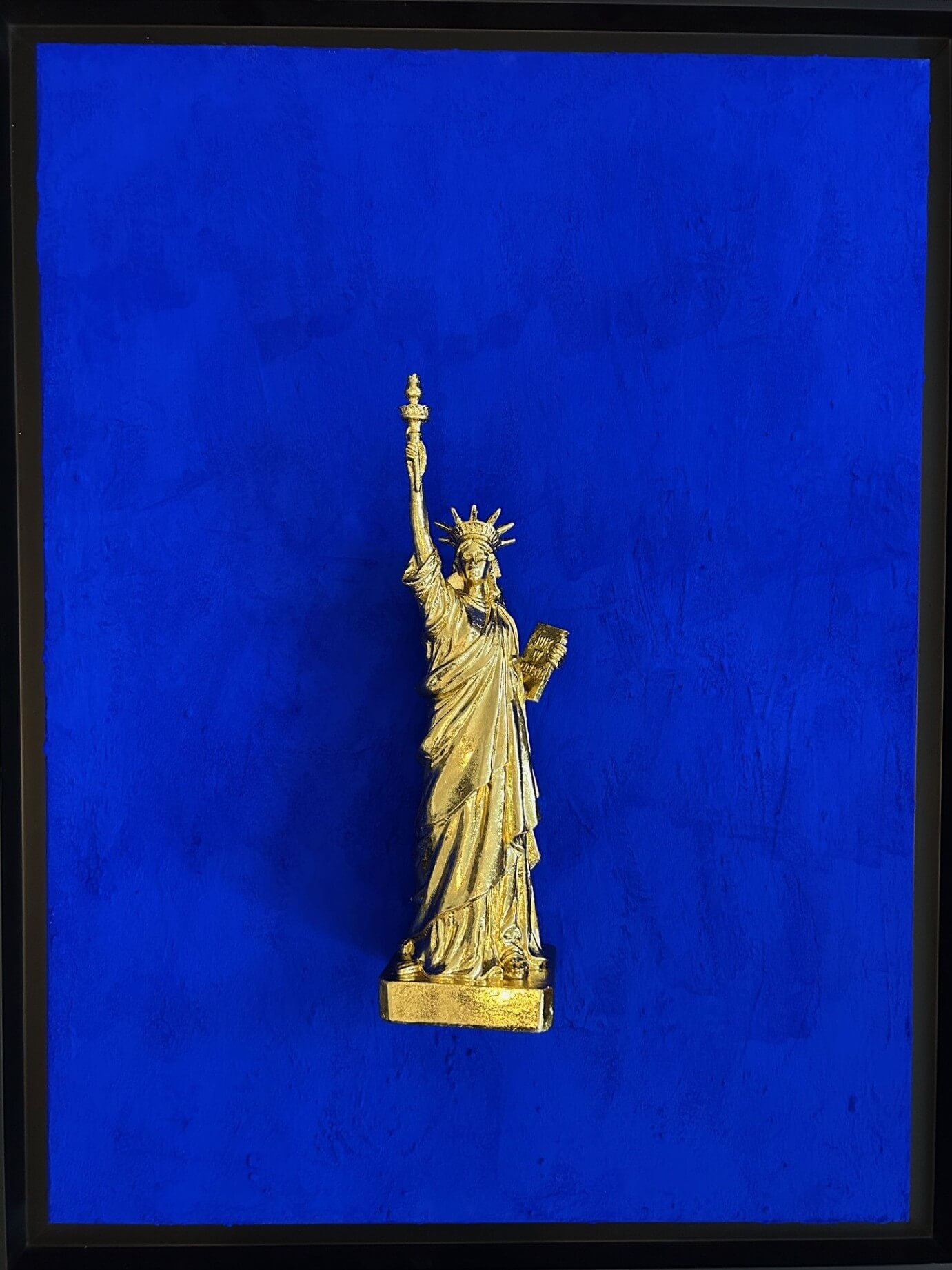 Seb Machten contemporary artwork with gold Statue of Liberty sculpture on ultramarine blue surface