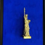 Seb Machten contemporary artwork with gold Statue of Liberty sculpture on ultramarine blue surface