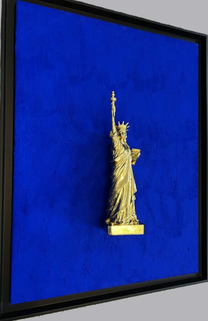 Seb Machten contemporary artwork with gold Statue of Liberty sculpture on ultramarine blue surface