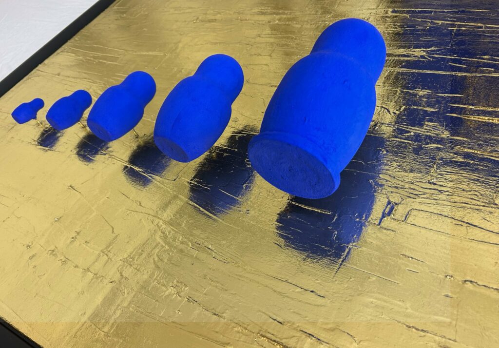 Seb Machten contemporary artwork with blue matryoshka figures arranged in progression on textured gold leaf surface background