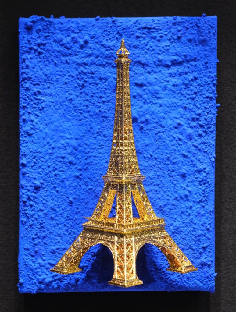 Seb Machten contemporary artwork with gold Eiffel Tower sculpture on deep ultramarine blue surface