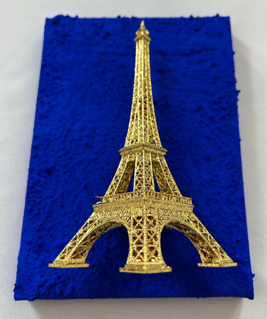 Seb Machten contemporary artwork with gold Eiffel Tower sculpture on deep ultramarine blue surface
