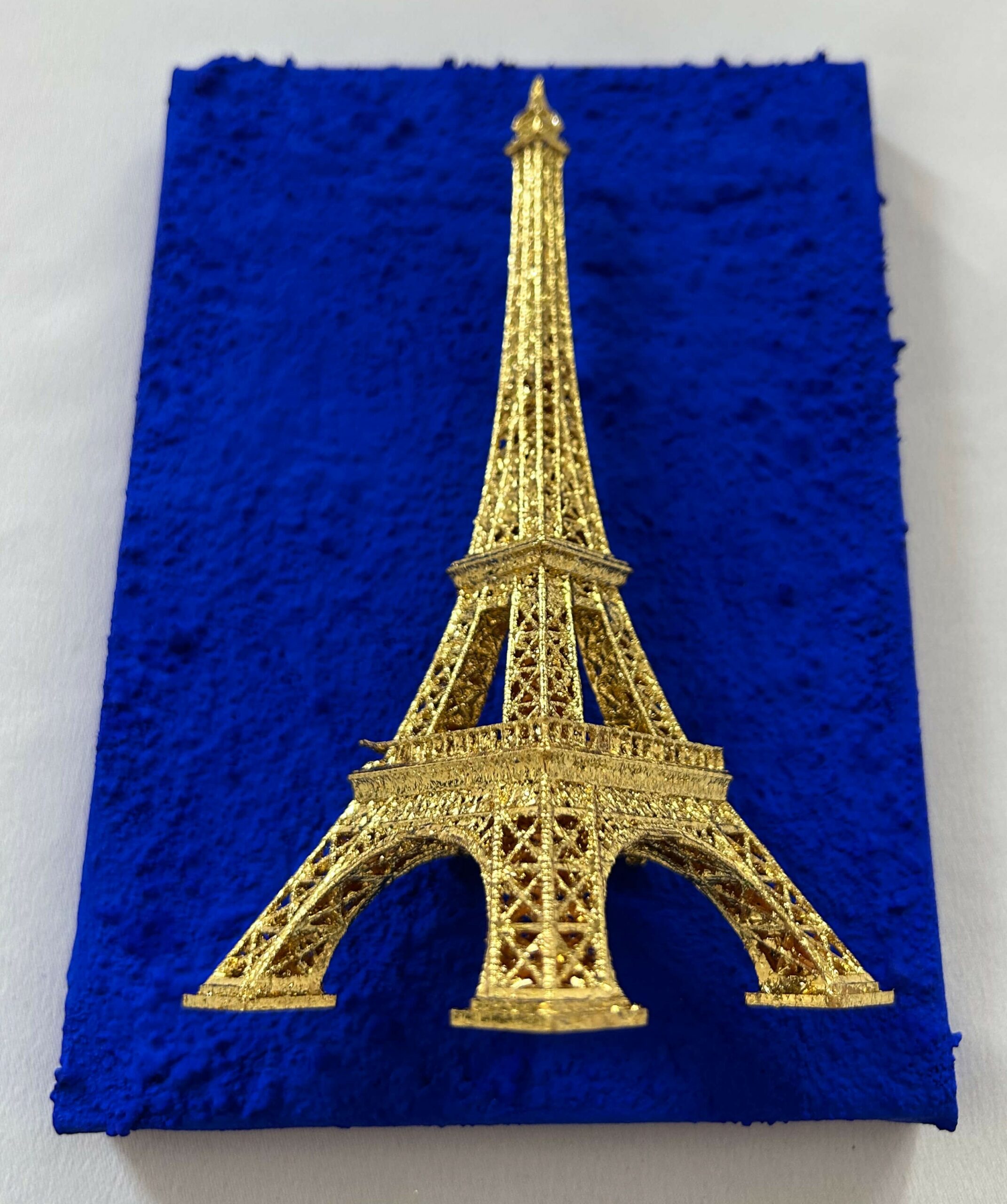 Seb Machten contemporary artwork with gold Eiffel Tower sculpture on deep ultramarine blue surface