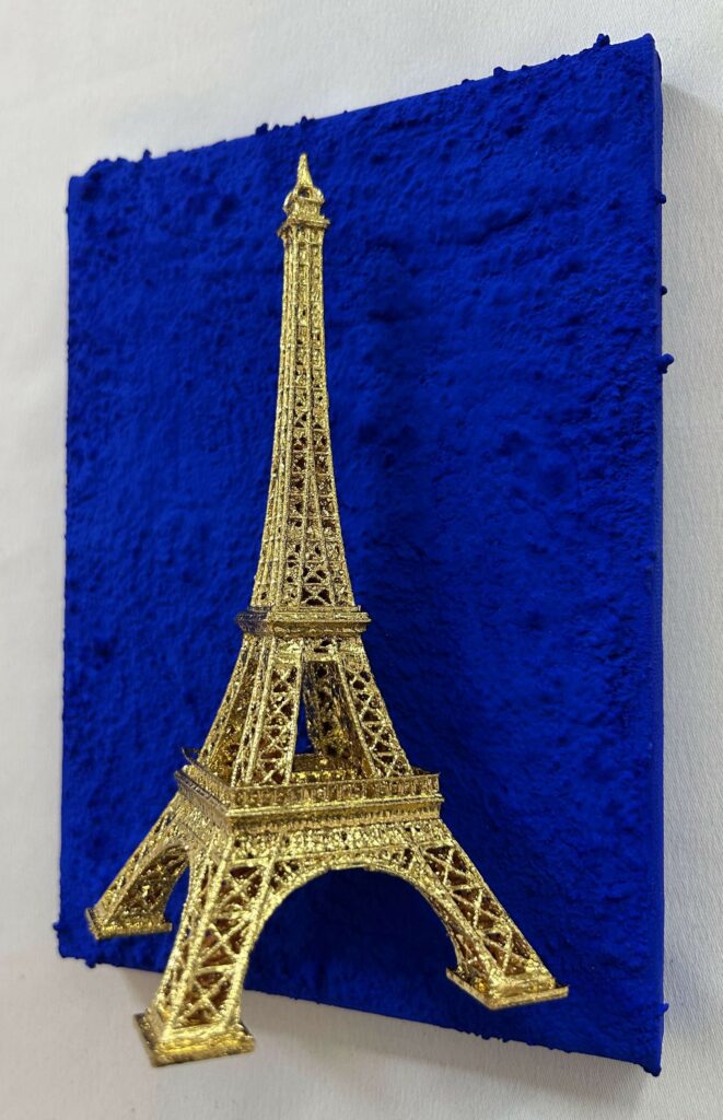 Seb Machten contemporary artwork with gold Eiffel Tower sculpture on deep ultramarine blue surface