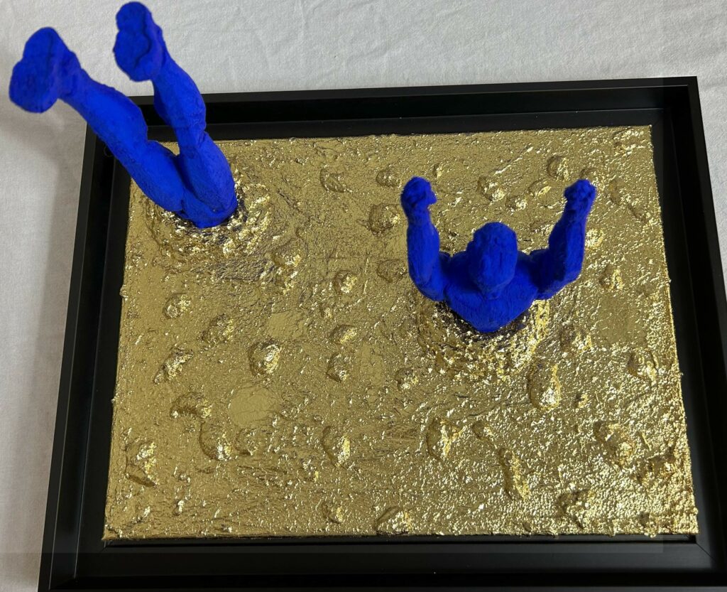 Seb Machten Contemporary pop art sculpture of two blue flying figures diving and emerging on textured gold background, exploring inner journey and self-reflection