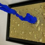 Seb Machten Contemporary pop art sculpture of two blue flying figures diving and emerging on textured gold background, exploring inner journey and self-reflection