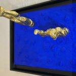 Seb Machten Contemporary pop art sculpture of two gold flying figures emerging and diving into textured gold surface, exploring illusion of escape and inner tension