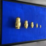 Seb Machten contemporary artwork with gold matryoshka figures evolving in size on deep ultramarine surface