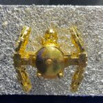 Seb Machten contemporary artwork with gold starfighter built from construction bricks projecting from textured silver surface