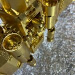 Seb Machten contemporary artwork with gold starfighter built from construction bricks emerging from lunar textured surface