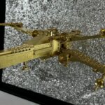 Seb Machten contemporary artwork with gold starfighter built from construction bricks emerging from lunar textured surface