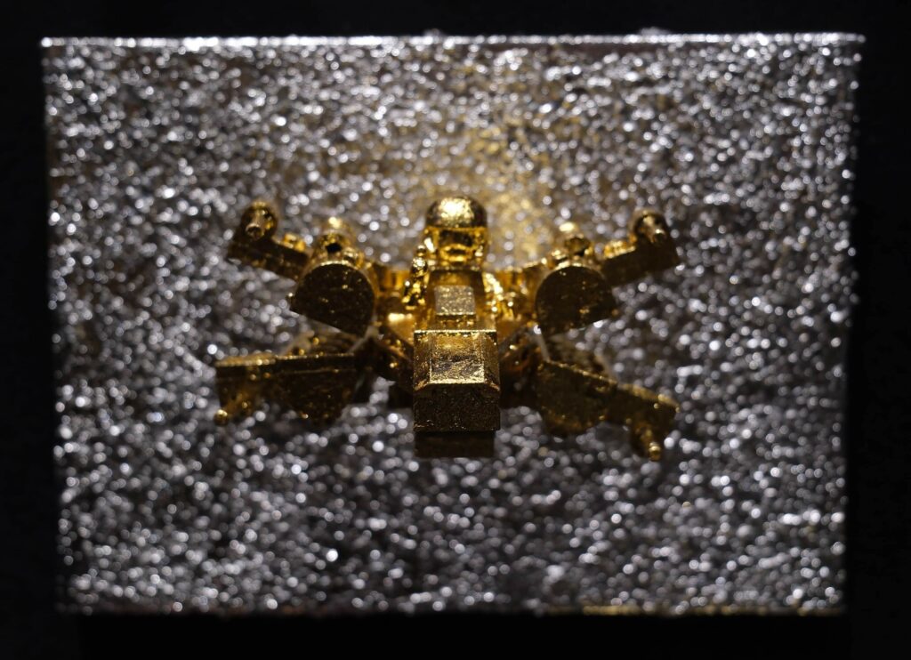 Seb Machten contemporary artwork with gold starfighter built from construction bricks projecting from textured silver surface