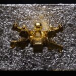 Seb Machten contemporary artwork with gold starfighter built from construction bricks projecting from textured silver surface