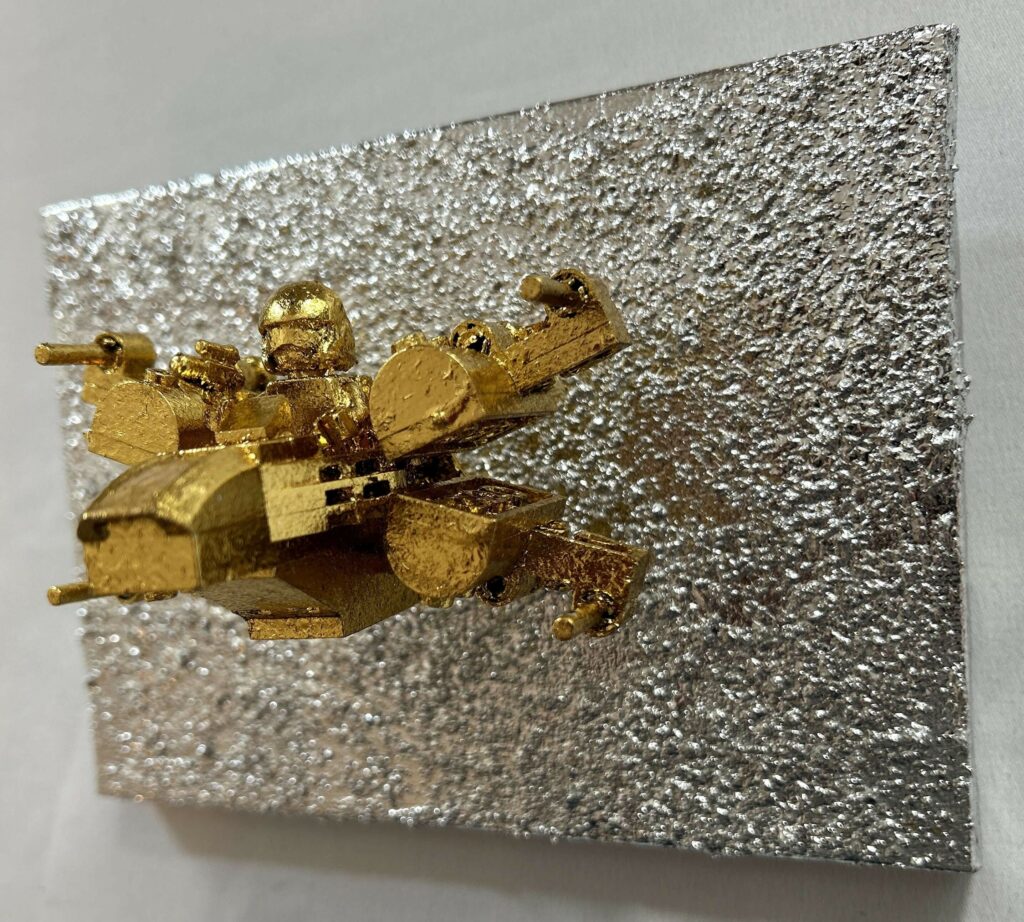 Seb Machten contemporary artwork with gold starfighter built from construction bricks projecting from textured silver surface