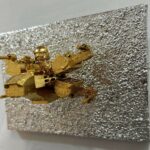 Seb Machten contemporary artwork with gold starfighter built from construction bricks projecting from textured silver surface