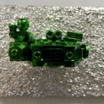Seb Machten contemporary artwork with green starfighter built from construction bricks projecting from textured silver surface