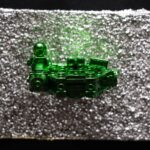 Seb Machten contemporary artwork with green starfighter built from construction bricks projecting from textured silver surface