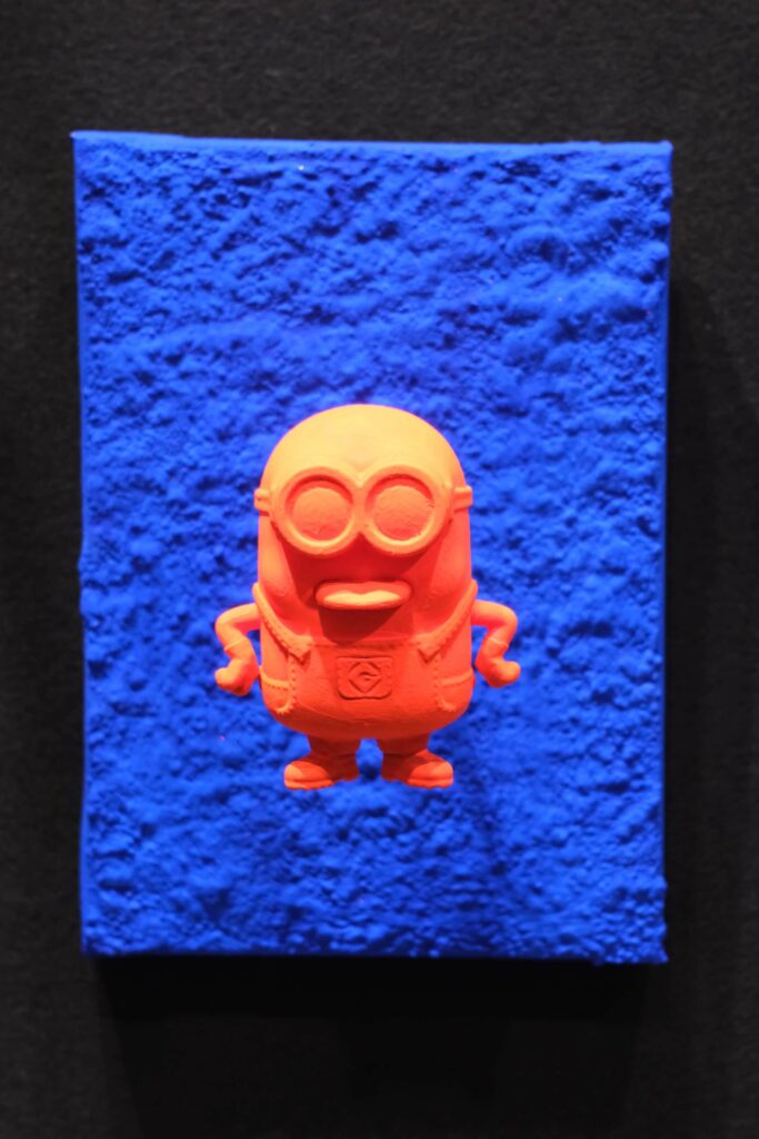 Seb Machten contemporary pop art sculpture with fluorescent orange minion-inspired figure on ultramarine textured surface